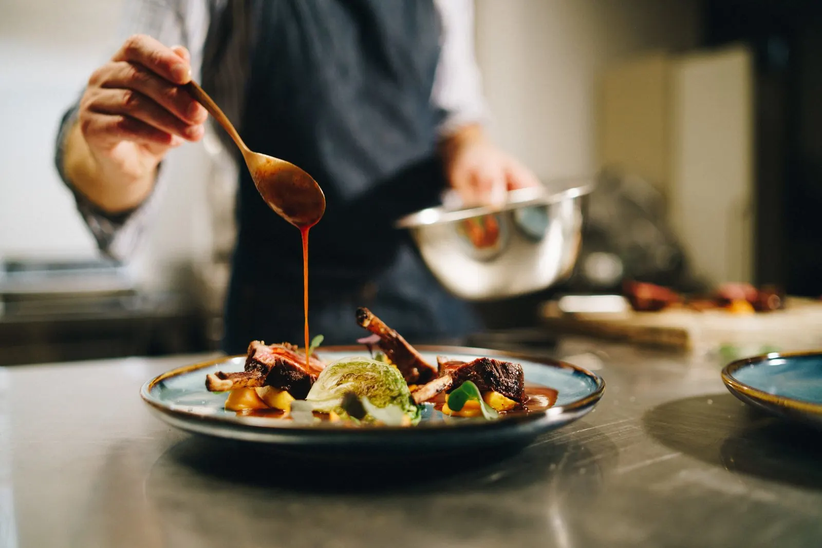 Chef qui nappe une assiette de sauce en cuisine
